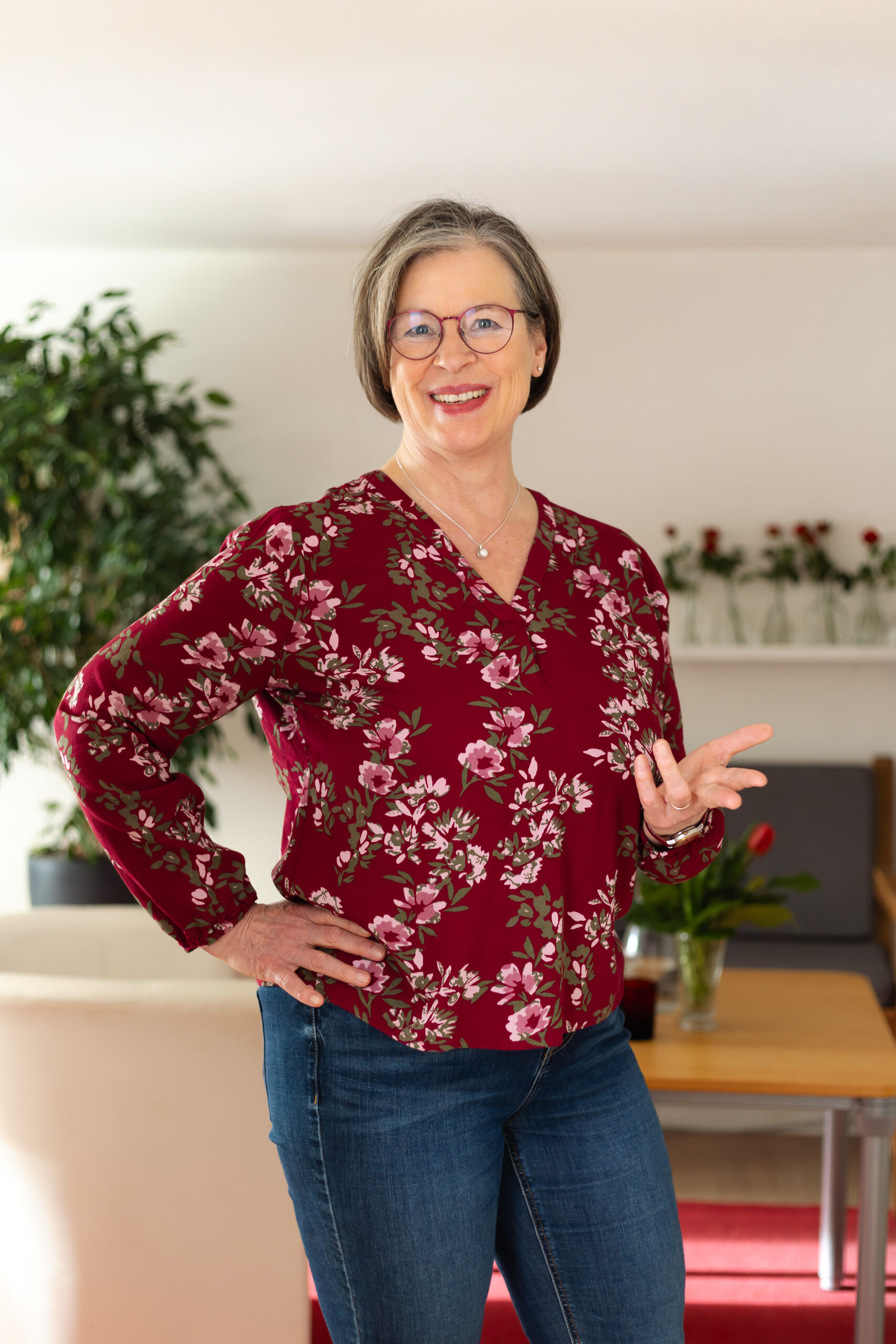 Portrait Antje Müller mit Laptop an einem Tisch mit einem Blumenstrauss und 2 Wassergläsern